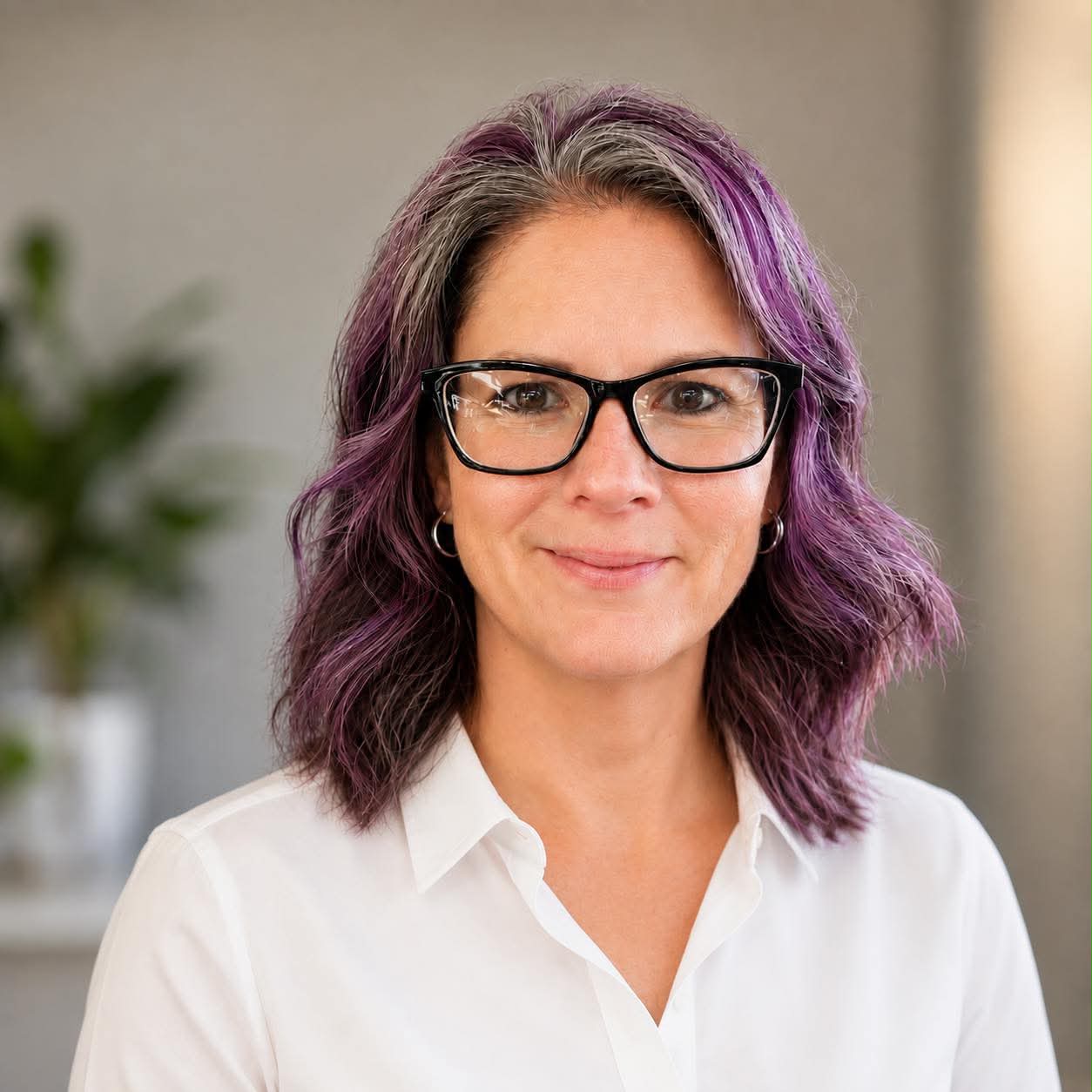 A woman with shoulder-length wavy purple hair, wearing glasses and a white shirt, smiles gently. The background is softly blurred with a green plant visible, creating the perfect inviting image for a website popup or popup header.